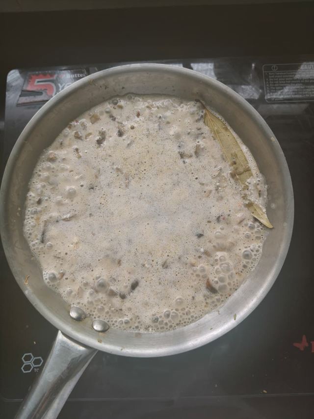 The paneer paste bubbling in the pan with the mushrooms, a bay leaf floating on the surface.