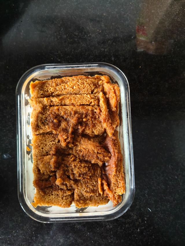 Glass dish lined with a base layer of coffee-soaked Toastea rusks, arranged edge to edge.