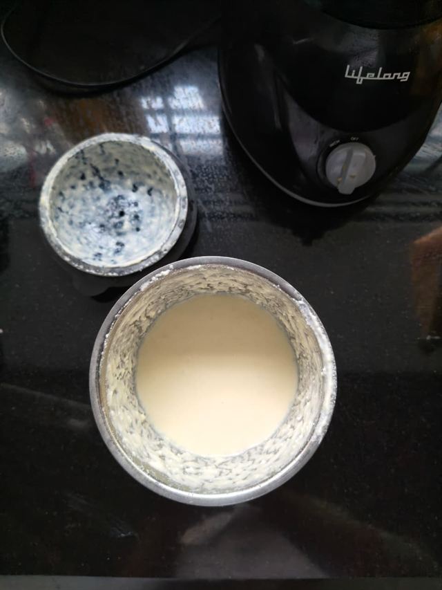 Two mixer jars on a countertop — one scraped nearly clean, the other filled with smooth, pale blended paneer cream.